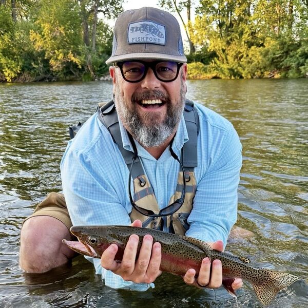 Tony Johannsen holding a rainbow trout in a river